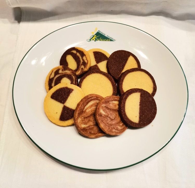 Ein Teller mit verschiedenen Keksformen in Gelb- und Schokoladenfarben.